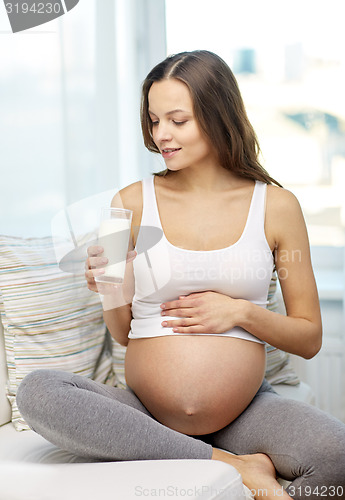 Image of happy pregnant woman drinking milk at home