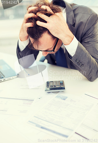 Image of businessman with papres, laptop and calculator