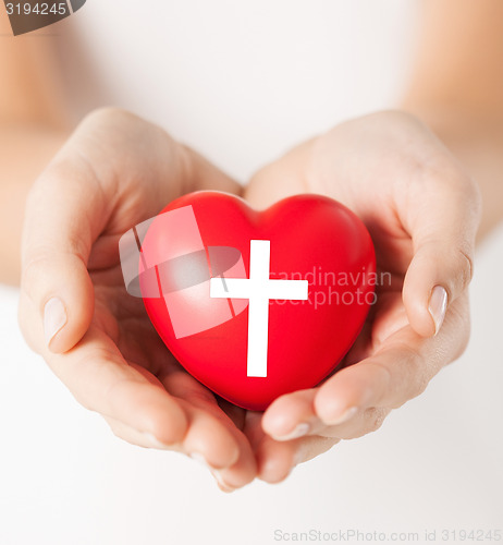 Image of female hands holding heart with cross symbol