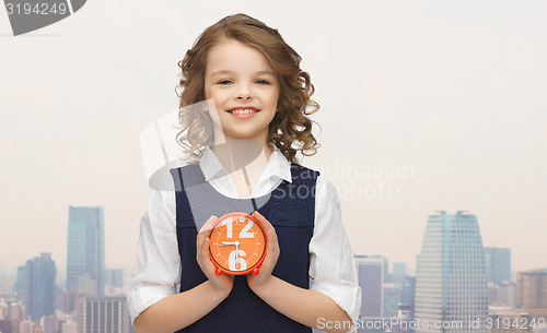 Image of happy girl with alarm clock over city background