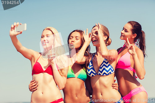 Image of group of smiling women making selfie on beach