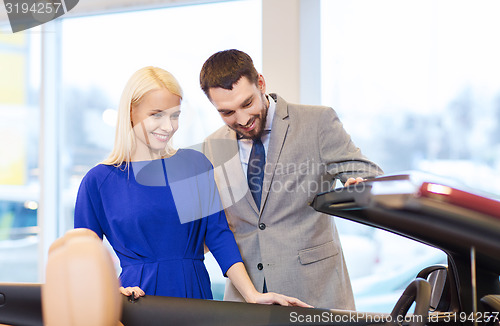 Image of happy couple buying car in auto show or salon