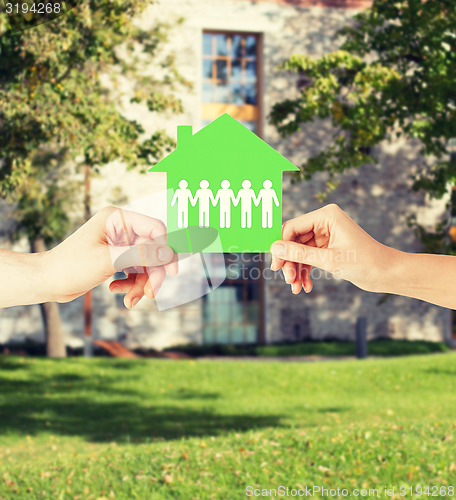 Image of man and woman hands with paper house