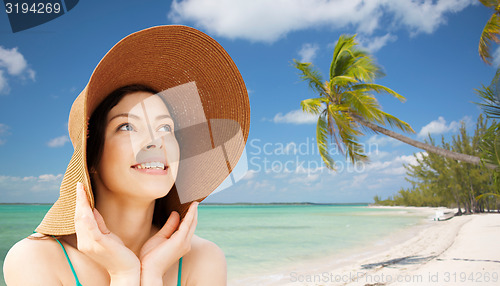 Image of happy young woman in straw hat on tropical beach