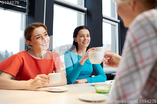 Image of happy young women drinking tea or coffee at cafe