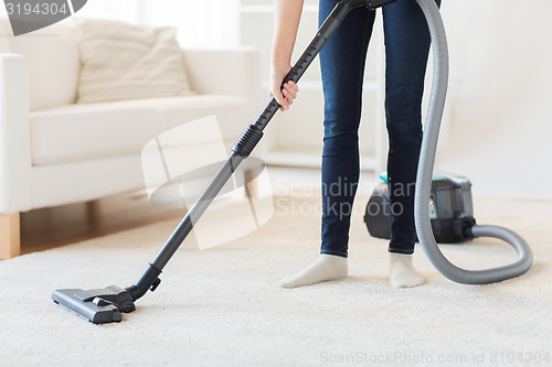 Image of close up of woman legs with vacuum cleaner at home