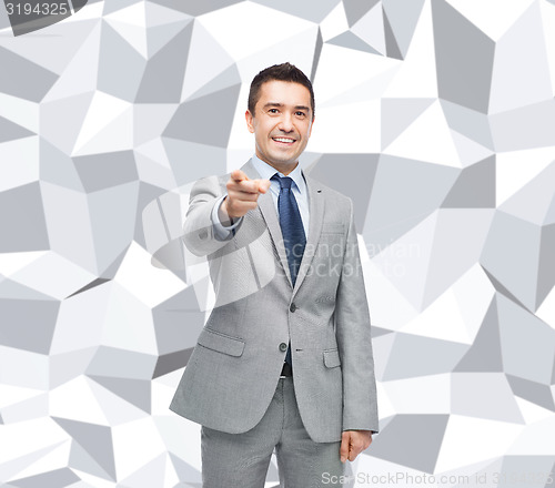 Image of happy smiling businessman in suit pointing at you