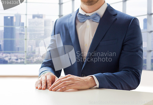 Image of close up of man in suit and bow-tie at table