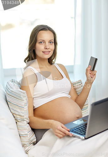 Image of pregnant woman with laptop and credit card at home