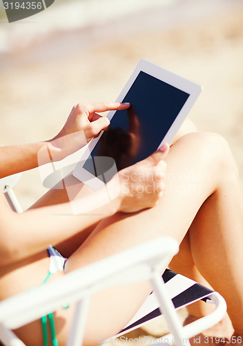 Image of girl looking at tablet pc on the beach