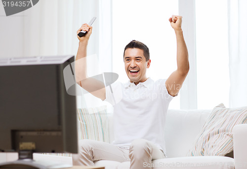 Image of smiling man watching sports at home