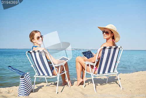 Image of happy women with tablet pc sunbathing on beach