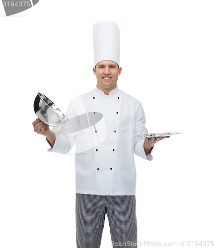 Image of happy male chef cook opening cloche