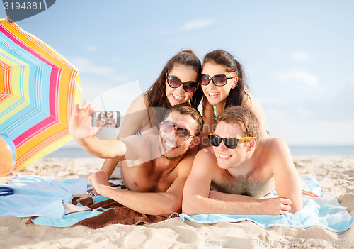 Image of happy friends taking selfie by smartphone on beach