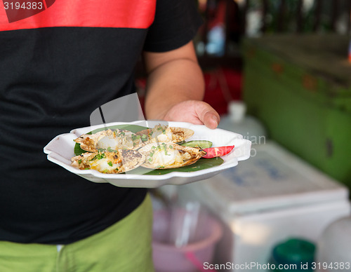 Image of close up of hand holding seafood at street market