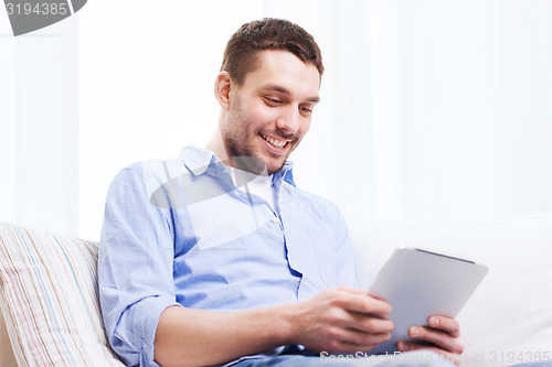 Image of smiling man with tablet pc and cup at home