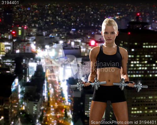 Image of sporty woman with heavy steel dumbbells