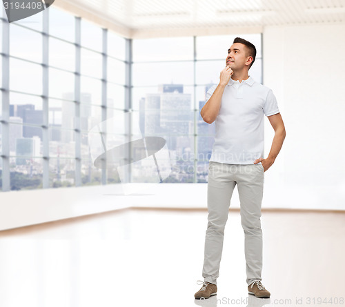 Image of smiling man with hands in pockets looking up