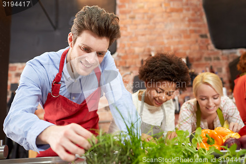 Image of happy friends cooking and decorating dishes