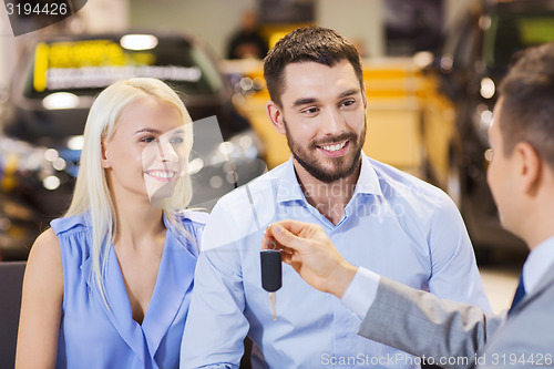 Image of happy couple with car dealer in auto show or salon