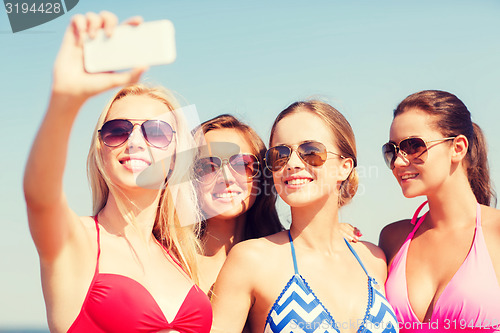 Image of group of smiling women making selfie on beach