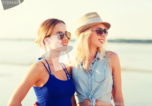 Image of two smiling women in sunglasses on beach