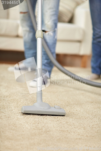 Image of close up of human legs and vacuum cleaner at home