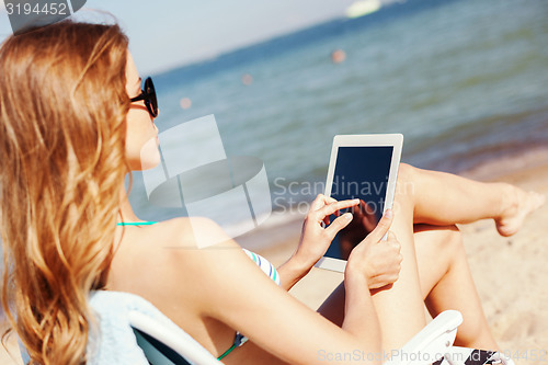 Image of girl looking at tablet pc on the beach