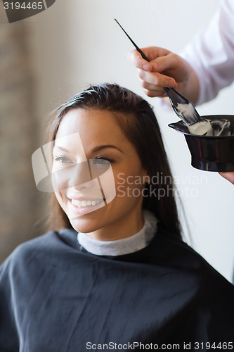 Image of happy woman with stylist coloring hair at salon