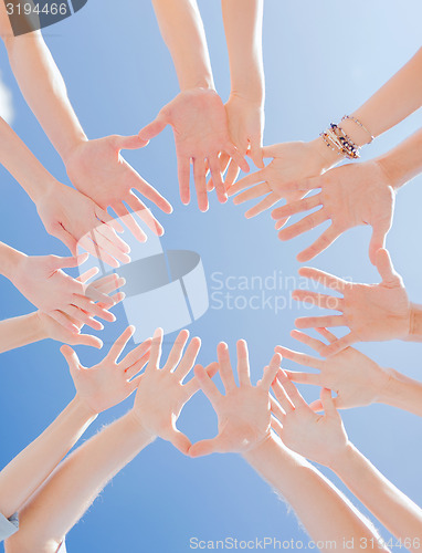 Image of many hands over blue sky background