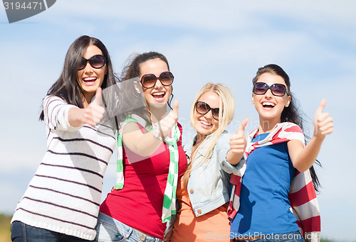 Image of happy teenage girls showing thumbs up on beach