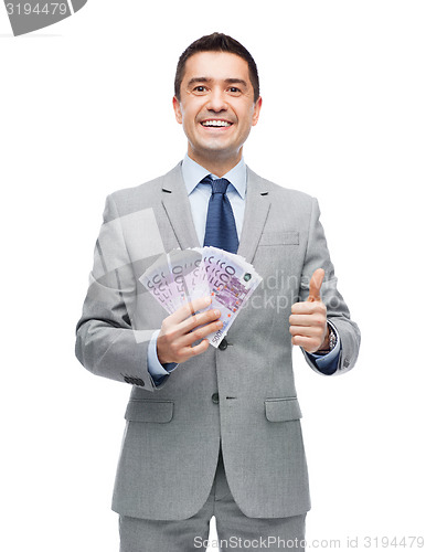 Image of smiling businessman with money showing thumbs up