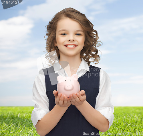 Image of happy girl holding piggy bank on palms