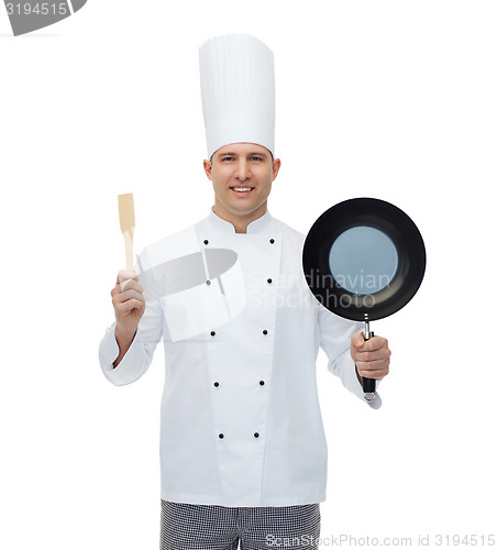 Image of happy male chef holding frying pan and spatula