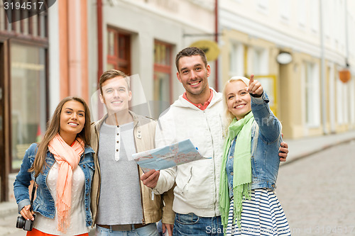 Image of group of smiling friends with map and photocamera