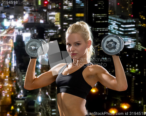 Image of sporty woman with heavy steel dumbbells