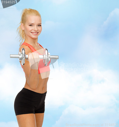 Image of young sporty woman with heavy steel dumbbell