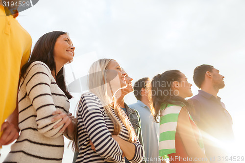 Image of group of happy friends looking up on beach