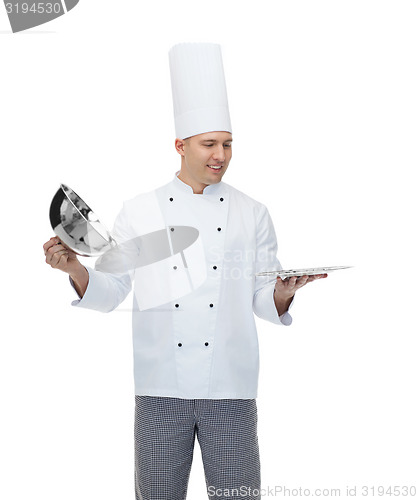 Image of happy male chef cook opening cloche