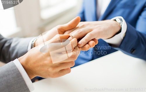 Image of close up of male gay couple hands and wedding ring