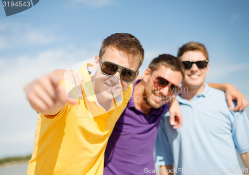 Image of smiling friends in sunglasses pointing at you