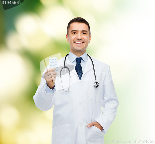 Image of smiling male doctor in white coat with tablets