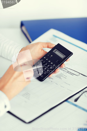 Image of woman hand with calculator and papers