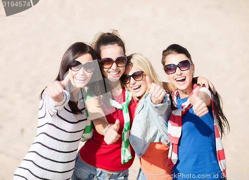 Image of happy teenage girls showing thumbs up on beach