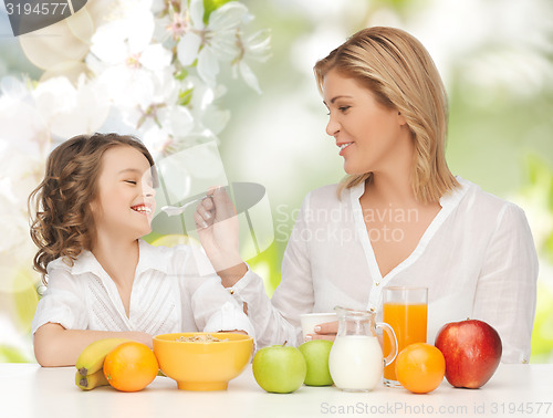 Image of happy mother and daughter eating breakfast