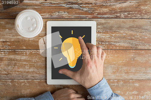 Image of close up of hands with ligting bulb on tablet pc