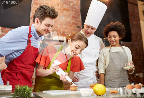 Image of happy friends and chef cook baking in kitchen