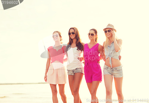 Image of group of smiling women in sunglasses on beach
