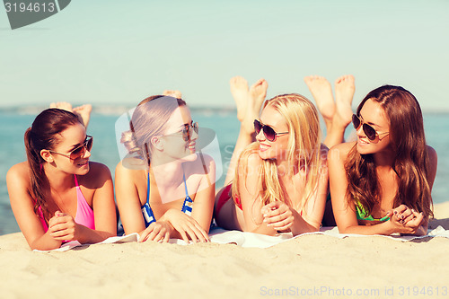 Image of group of smiling women in sunglasses on beach