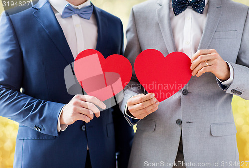 Image of close up of male gay couple holding red hearts